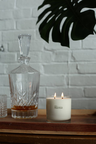 A candle and a bottle of whiskey on a table.