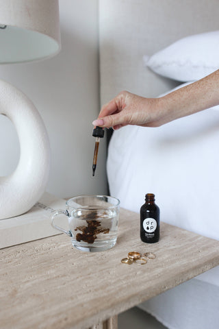 A person pouring oil into a glass, creating a golden stream.
