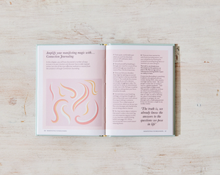 A book with pink and white pages resting on a wooden surface, providing a visually appealing contrast.