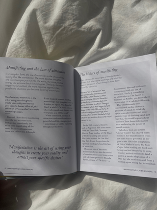 An open book on a bed with a white sheet.