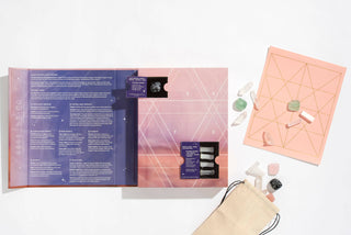 A book with a bag, a card, and a stone - a collection of objects on a table, representing different elements.