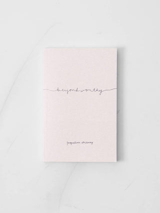 A pink notebook with the words "Beyond worthy" written on it, symbolizing a joyful and fulfilling ending.