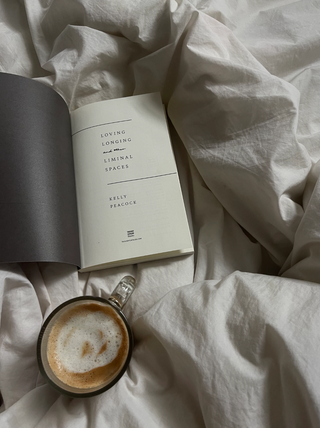 A cozy scene with a cup of coffee and a book on a neatly made bed.