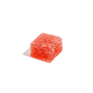 Single red sugar cube on white background.