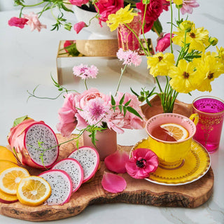 Colorful flowers and fruit arranged on a table.