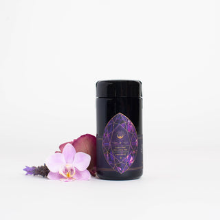 A jar of lavender oil surrounded by purple flowers.