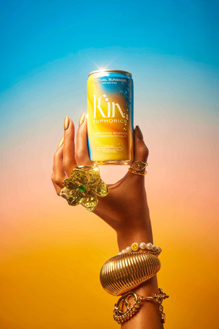 A vibrant ad for Kin Europhics, featuring a refreshing bottle of the drink surrounded by colorful fruits and herbs.