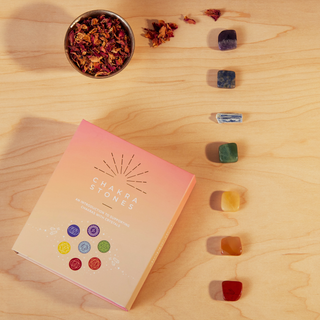 A box of colorful chakra stones next to a bowl of vibrant flowers.