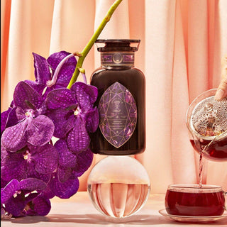  A jar of lavender oil surrounded by purple flowers.