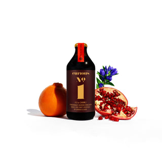 A bottle of wine placed beside an orange and pomegranate, creating a vibrant and enticing composition.