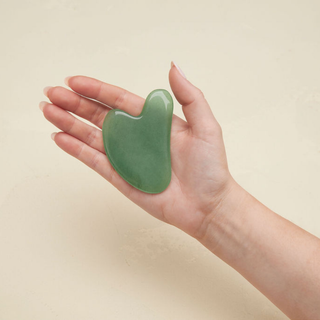 A person holding a green stone in their hand, showcasing its vibrant color and smooth texture.