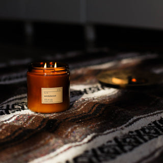 A lit candle on a rug in sunlight.