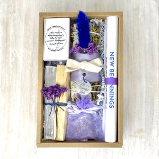 A purple and white candle, a book, and a note inside a box.
