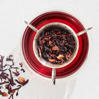 A close-up of a tea cup filled with red hibiscus tea, showcasing its vibrant color and inviting aroma.